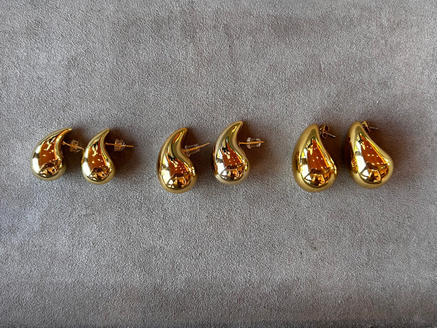 Un par de aretes de oro con una gota de oro en la parte inferior.